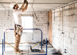 Electrician installer with a tool in his hands, working with cable on the construction site.